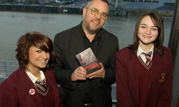 Alan Gibbons with pupils and one of his youth novels