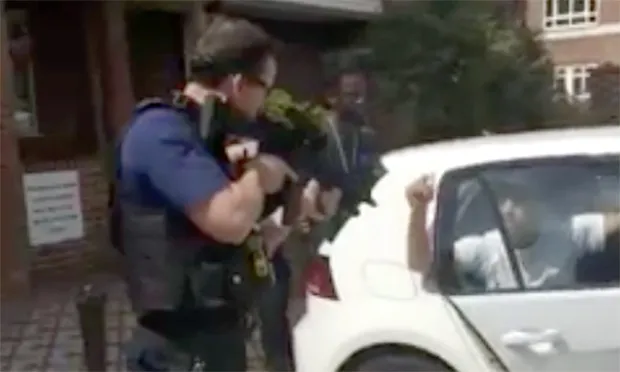 Armed police captured on video pointing assault rifles at two men holding their hands up